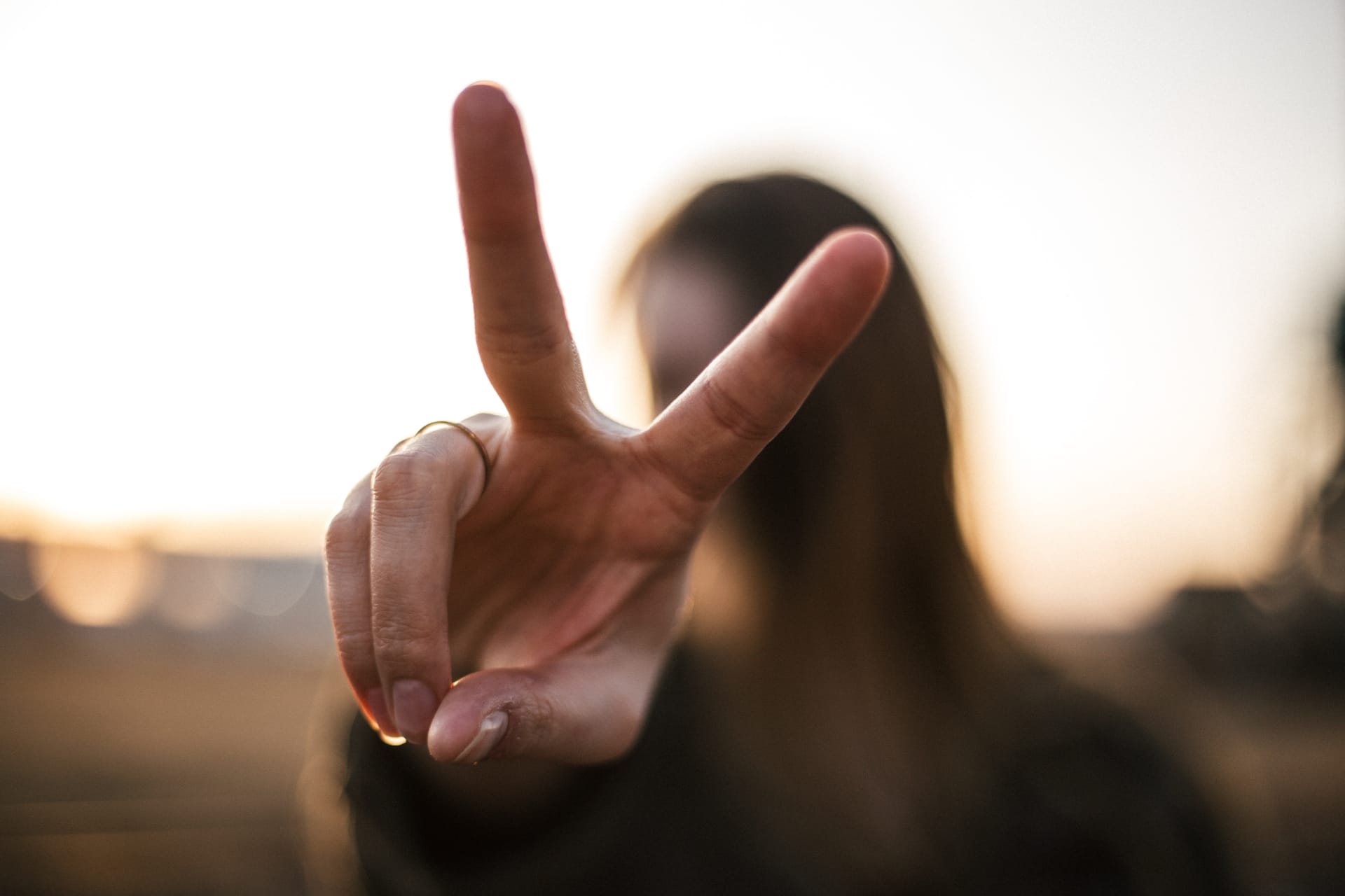 Eine junge Frau gestikuliert das Peace-Zeichen. Sinnbild für Toleranz und Akzeptanz.