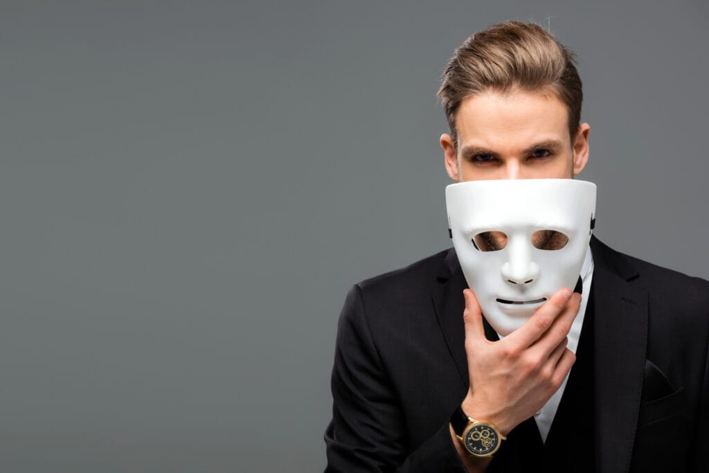 Ein Geschäftsmann zieht eine Maske vom Gesicht. Symbolisches Bild für einen authentischen Lebensstil.