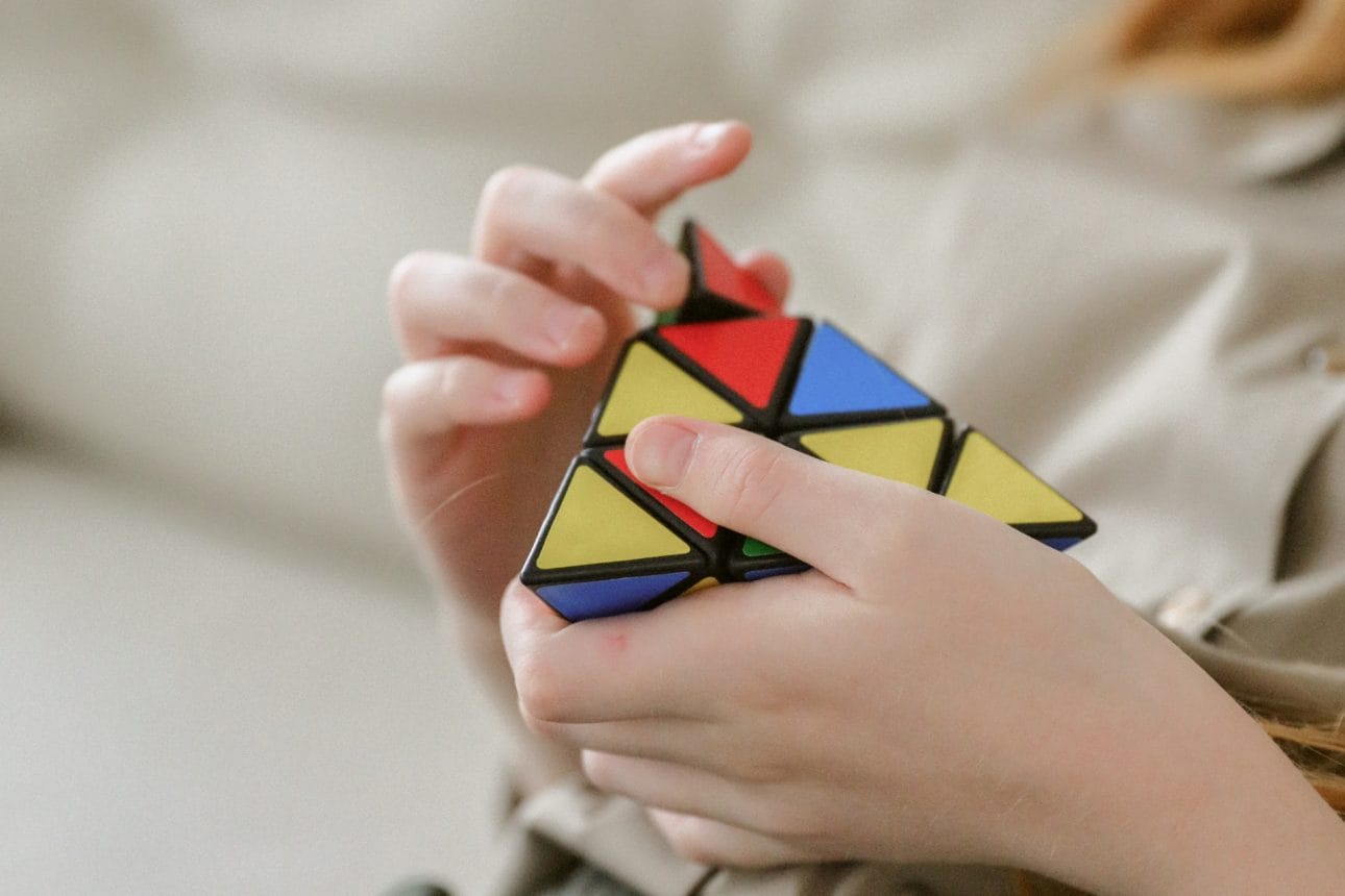 Eine junge Frau versucht konzentriert einen Rubik zu lösen. Sinnbild für lösungsorientiertes Handeln.