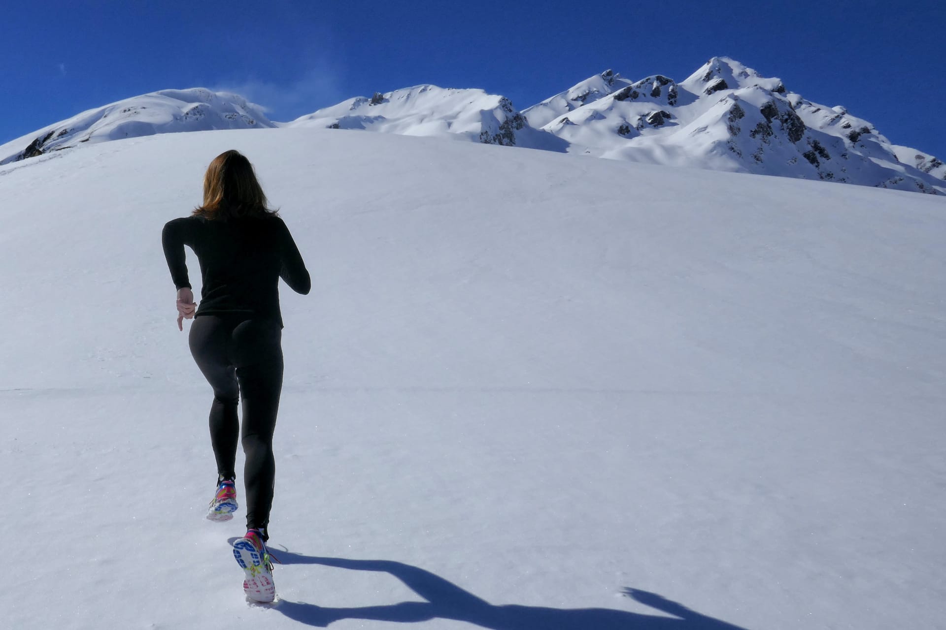 Eine Frau joggt im verschneiten Gebirge. Sinnbild für Resilienz.