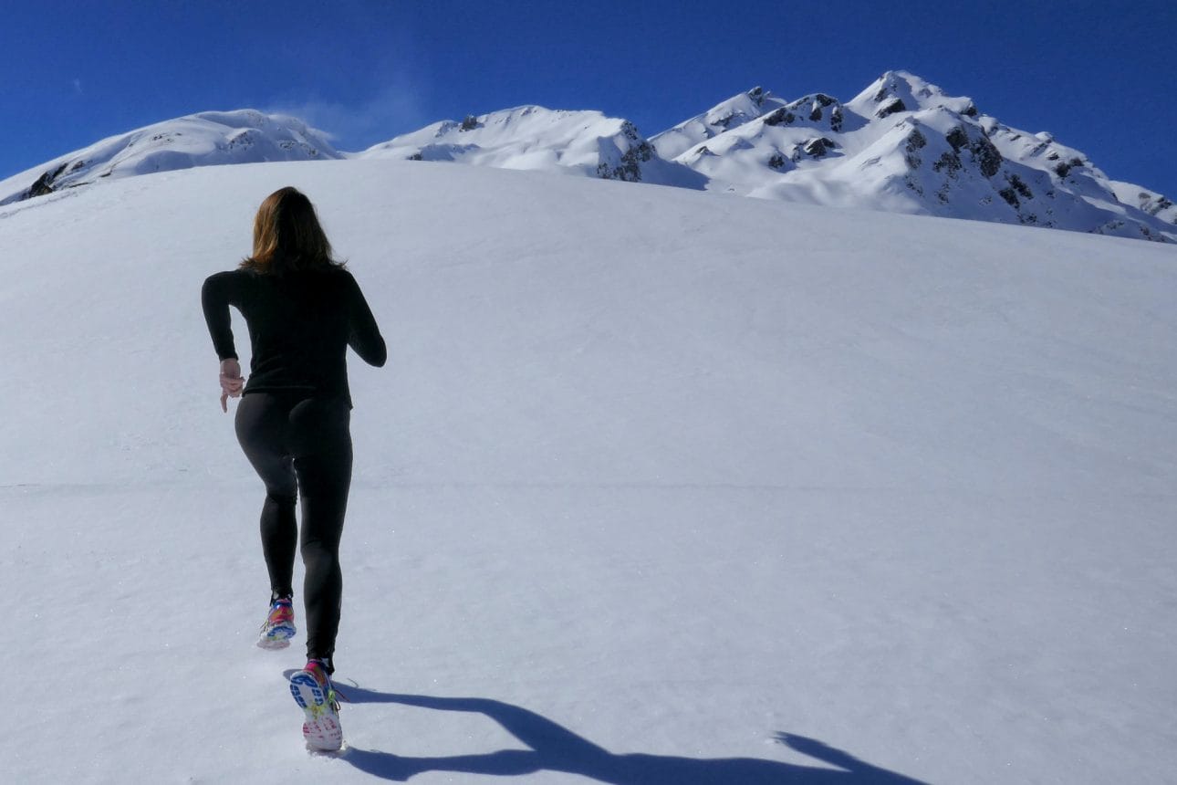 Eine Frau joggt im verschneiten Gebirge. Sinnbild für Resilienz.