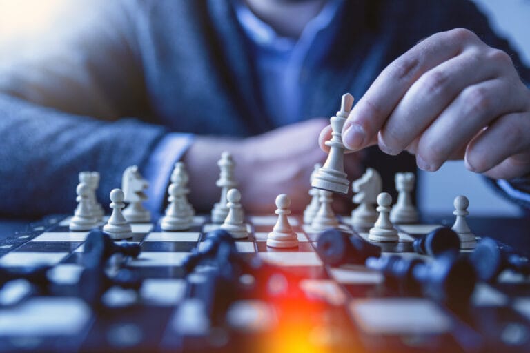 Ein Mann spielt einen Schachzug und räumt die Figur des Gegners weg. Sinnbild für strategisches Denken und Handeln als Führungskraft.