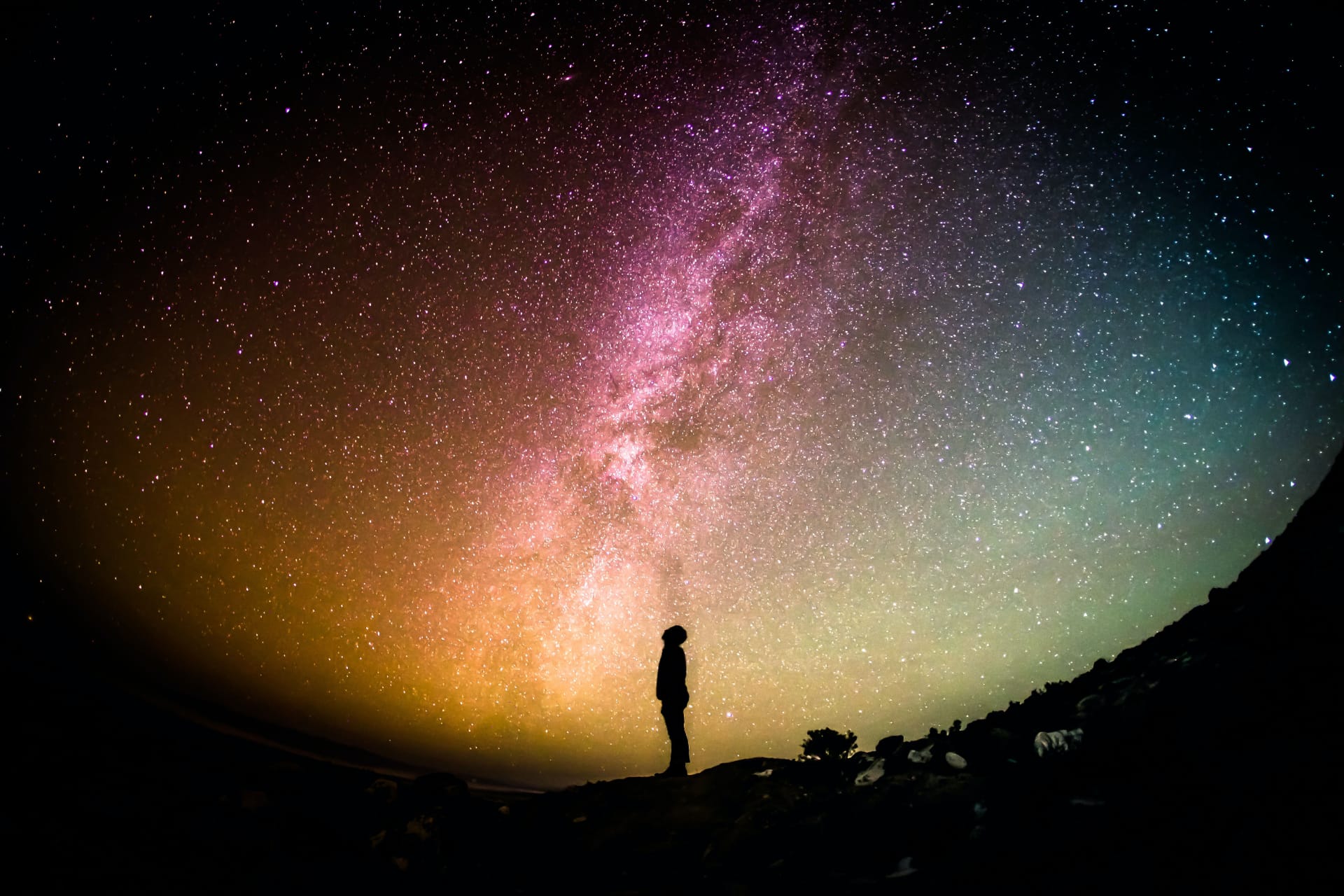 Ein Mann blick auf einen sternereichen Nachthimmel im Gebirge. Die Szene sieht magisch aus und schenkt Zuversicht für die Zukunft.