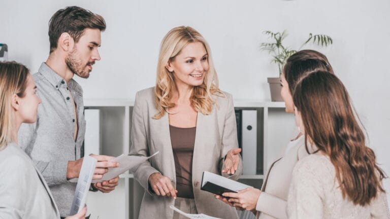 Eine Führungskraft spricht auf eine freundliche und zuvorkommende Art mit ihren Mitarbeitern. Symbolisches bild für Macht und Verantwortung in der Mitarbeiterführung.