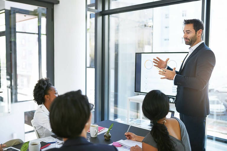 Ein Coach hält eine Präsentation vor einer Gruppe von Menschen während einer proCEO Ausbildung.