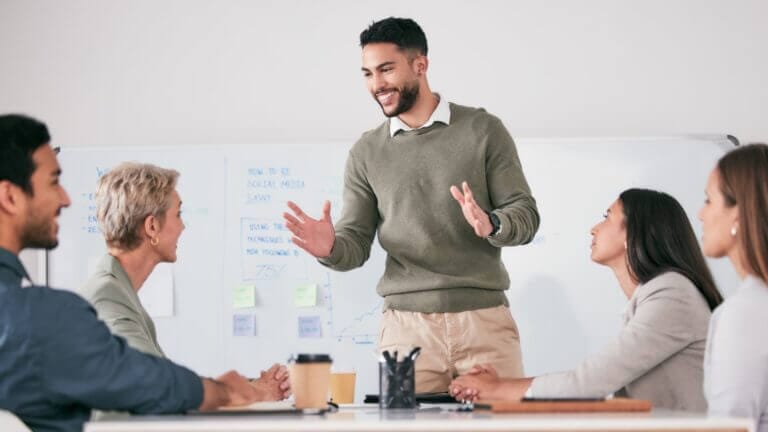 Eine Führungskraft spricht zu ihrem Team in einem Besprechungsraum. Symbolisches Bild für die Birkman-Methode im proCEO Online CAMPUS.