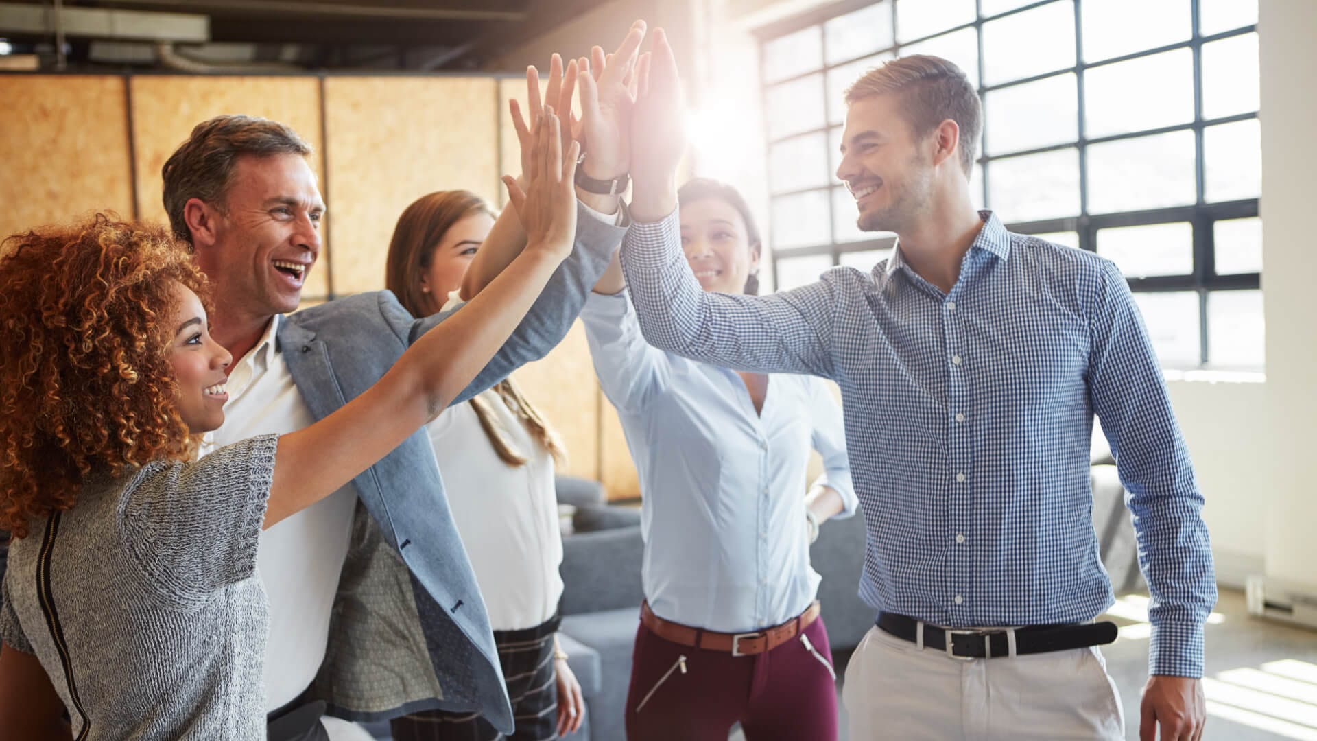 Ein Teamleiter gibt seinem gutgelaunten Team ein High five.