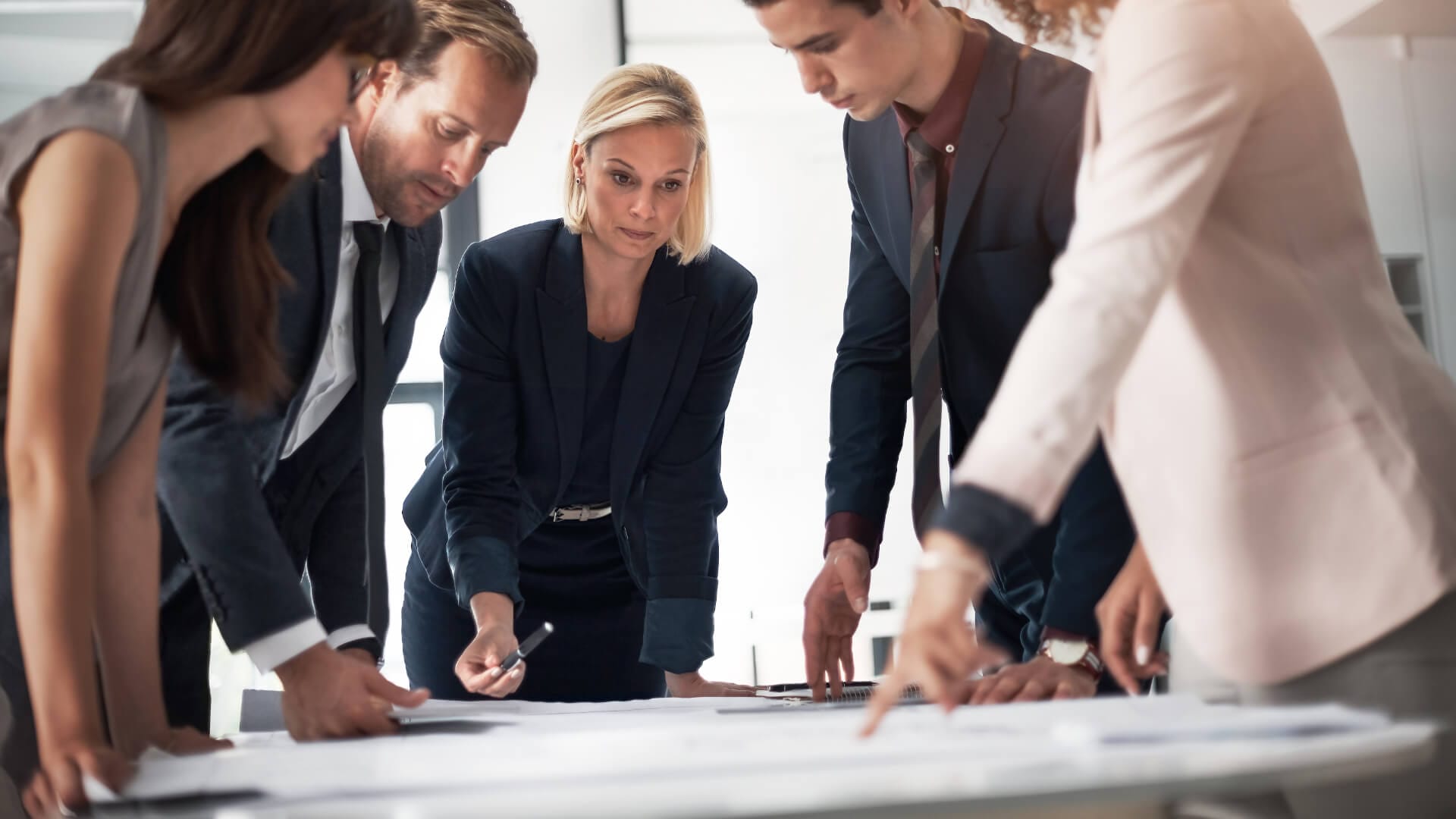 Eine Leiterin erklärt ihrem Team den Projektplan in einem Meetingraum.