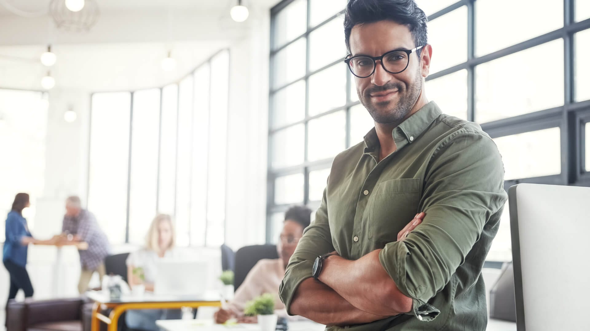 Ein kompetenter Mann in einem Büro mit verschränkten Armen.