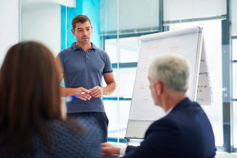 Ein Supervisor lehrt eine Gruppe von Führungskräften. Sinnbild für Supervision von Führungskräften zur Führungskräfteentwicklung nach einer Supervision Ausbildung.