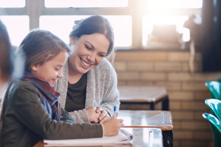 Eine Lehrerin begleitet eine Schülerin beim Lernen. Sinnbild für Supervision Ausbildung für Lehrende und Erziehende.