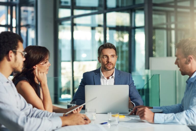 Ein Teamleiter bespricht mit seinen Mitarbeitenden im Meetingraum. Sinnbild für Supervision für Fach- und Führungskräfte in Wirtschaft und Management.